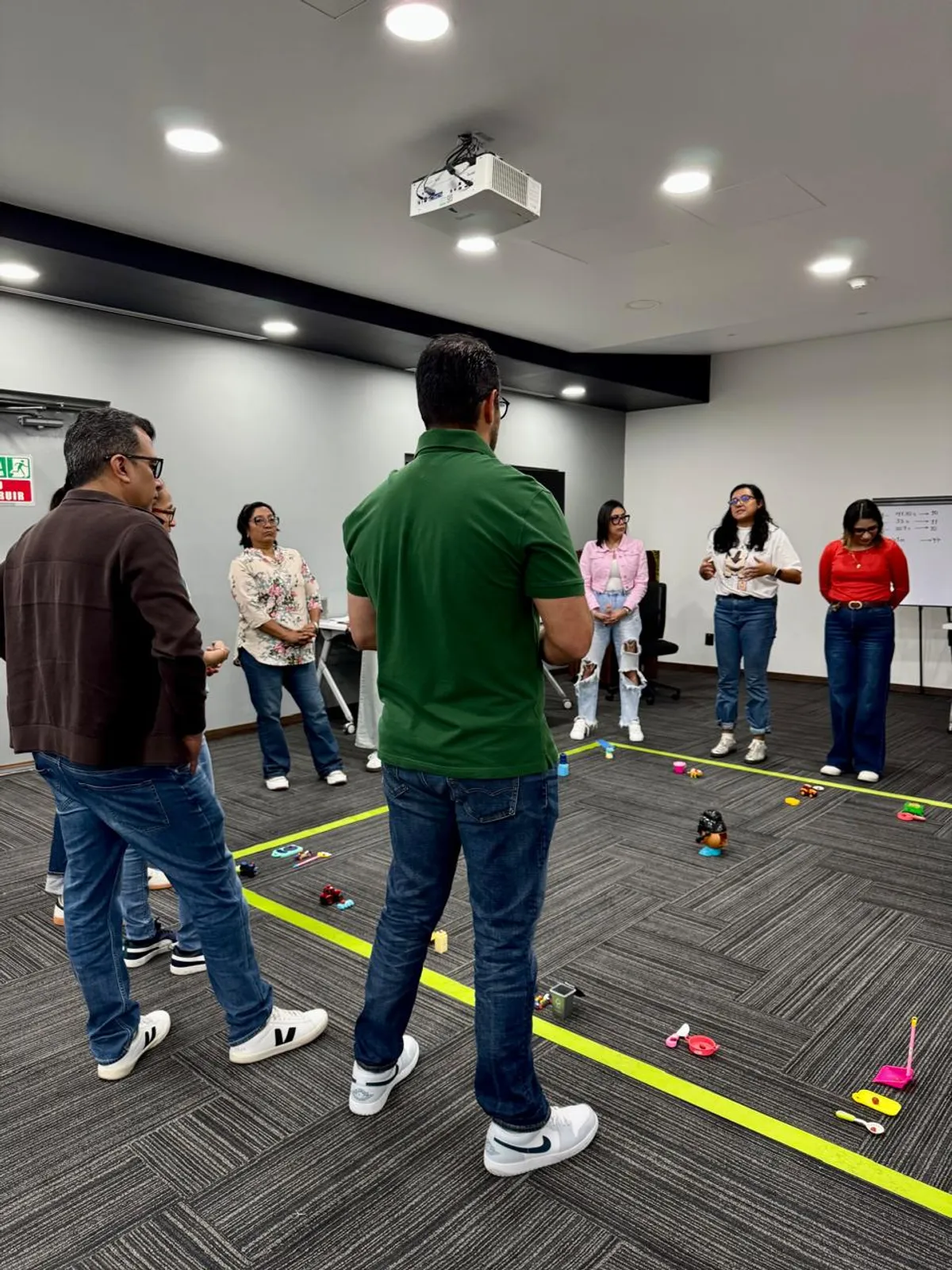 Grupo escuchando instrucciones de una dinamica con objetos en el piso