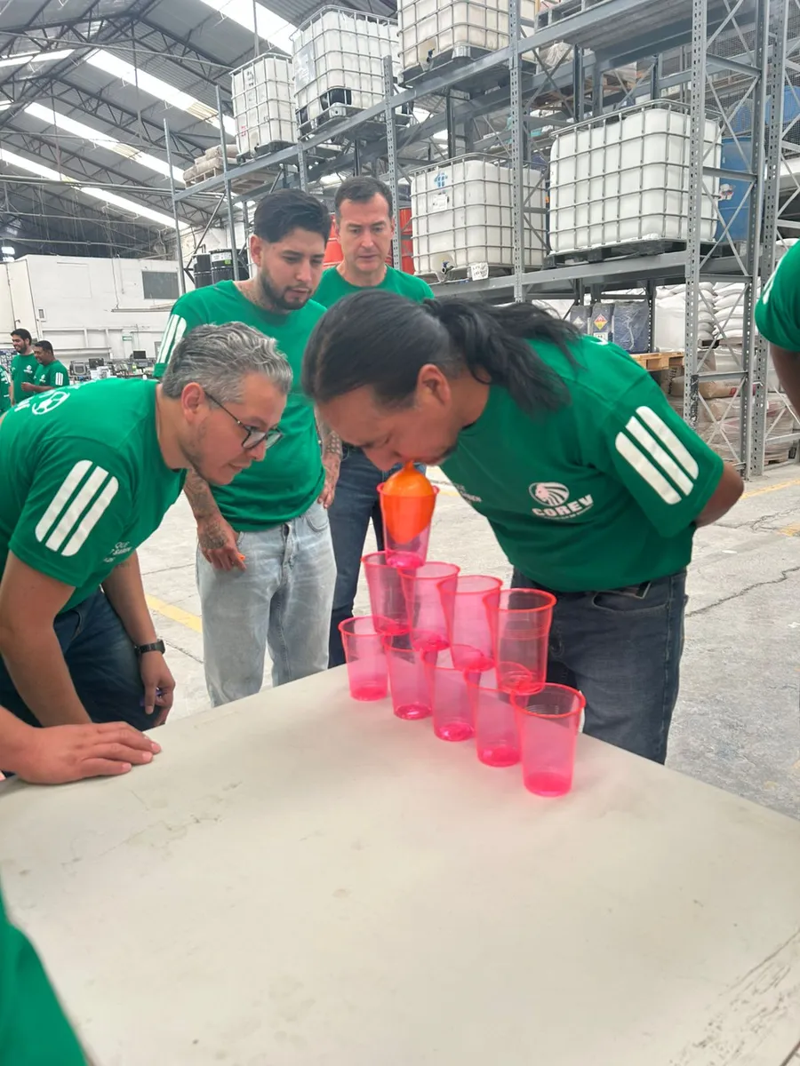 Participantes concentrados en un reto de equipo con vasos